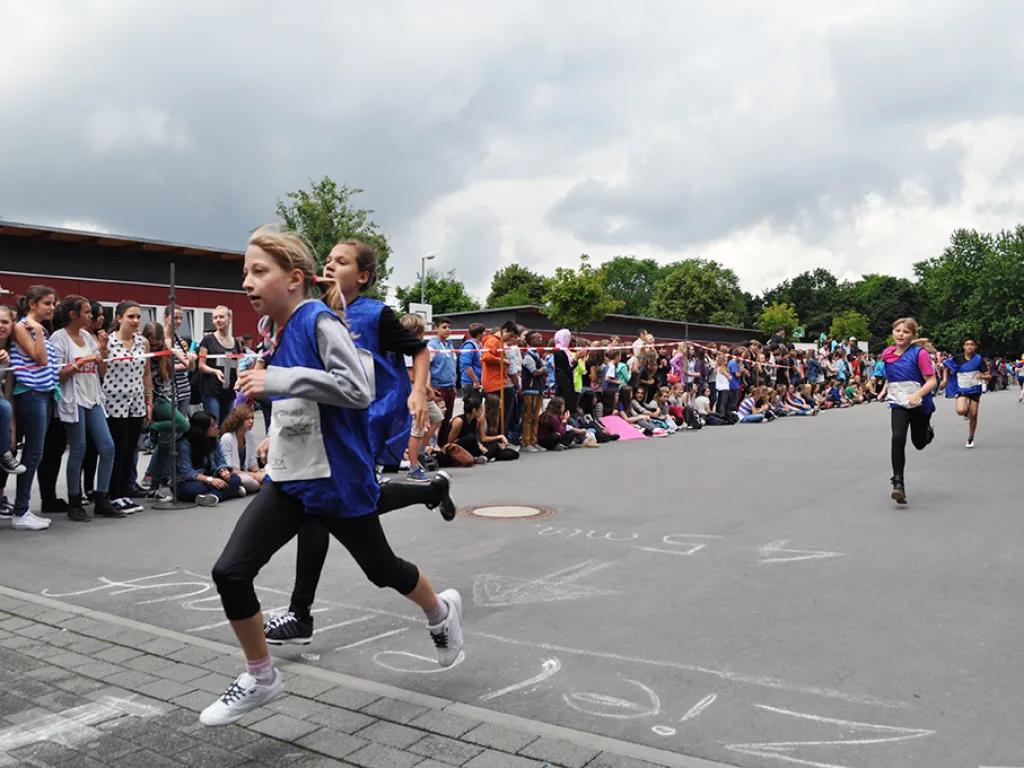 Läuferin auf der Strecke, dahinter jubelnde Zuschauer.